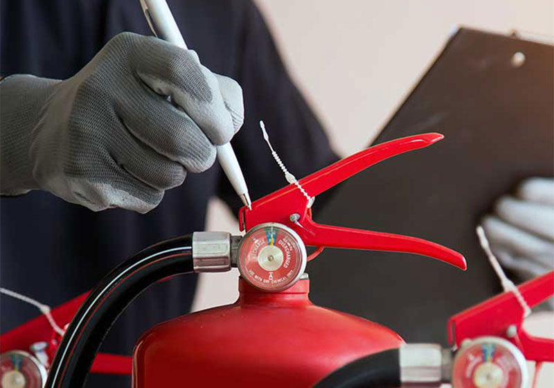 Inspecting a fire extinguisher with clipboard.