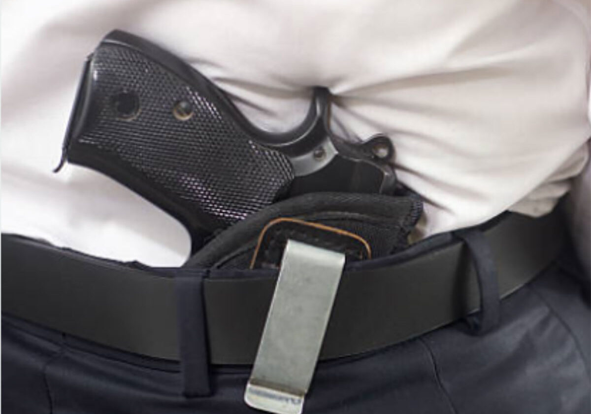 Gun tucked in waistband under shirt.